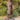 A bronze statue of Jesus Christ standing on a stone base looking up in pray, in Angela Johnson's work O My Father, 3/4 view photographed outdoors among green shrubs and trees.