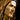 A close-up of a sculpted bust of Jesus Christ with long hair and a beard, in Angela Johnson's work Come Unto Me,shown in warm bronze and brown tones against a dark background.