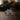 A rectangular clear acrylic or glass plaque stand on a wooden surface, displaying a black-and-white engraved photo Lazarus raising from the dead, based on sculpture Lazarus, Come Forth by Angela Johnson. The background is softly blurred with warm indoor lighting and greenery.