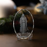 A clear crystal display stand shaped like an oval, holding a depiction of Jesus Christ referencing Matthew 14:23, set on a wooden surface with a softly blurred background.