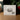 A white product box for 'Let He That Is Without Sin - Scene Gem V2' by angelajohnson.art, displayed on a wooden surface with a blurred background of green leaves and red berries.