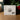The back of the packaging box for the 'I Give You Living Water' Gem V2 by angelajohnson.art, displayed on a wooden surface with a blurred background of green leaves and red berries.