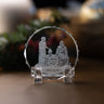 A clear acrylic crystal display stand featuring an engraved scene of Jesus and the woman at the well, with 'John 4:4-42' engraved on the base, set on a wooden surface with a blurred festive background.