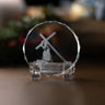 A clear crystal keepsake with an engraved image of Jesus carrying the cross, displayed on a clear acrylic stand on a wooden surface.
