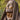 A bronze-toned statue of Jesus Christ with closed eyes, a beard, and a draped robe, in Angela Johnson's work O My Father, photographed outdoors against a blurred green background.