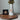 A white ceramic vase with dried green leaves in the neck, hanging from a rope pendant with a round bronze medallion featuring a profile portrait of Jesus Christ from Angela Johnson titled O My Father.